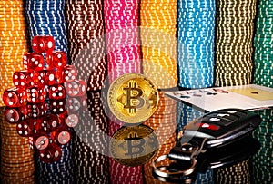 Gold coin bitcoin, red dice, cards and car keys on the background of colorful casino chips. Set for playing poker