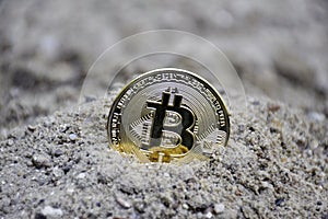 Gold coin bitcoin in the sand