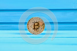 Gold coin crypto currency bitcoin on a blue table.