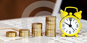 Gold coins and alarm clock on a laptop, online investment banner