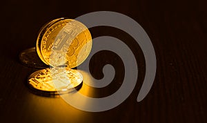 Gold coins of bitcoins on an office table on a dark background