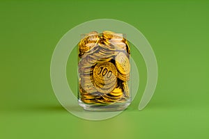 gold coins in glass jars on green background, coin savings concept
