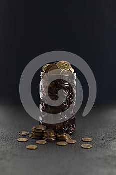 Gold coins in a piggy bank on a black background, growth in savings. Economic crisis and saving money. Donation to a charity fund