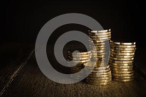 Gold coins in piles on a rustic background.