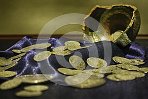 Gold coins scattered on silk cloth from a broken clay pot