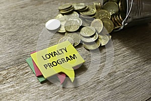 Gold coins and a stack of speech bubbles written with Loyalty Program on wooden background