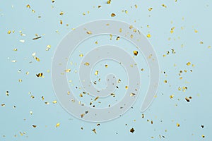 Gold confetti on light blue paper background. Festive holiday backdrop. Birthday congratulations Christmas New Year. Flat lay  top