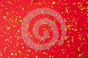 Gold confetti on red paper background. Festive holiday backdrop. Birthday congratulations Christmas New Year. Valentines Day. Flat