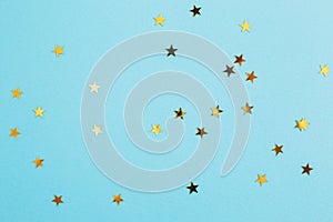 Gold confetti in the shape of a star on blue paper background. Festive holiday backdrop. Birthday congratulations Christmas New