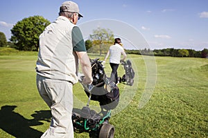 Gold couple walking on fairway with bags.