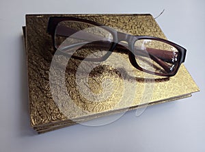 A gold cover reading book and sunglasses isolated a white background.