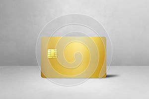 Gold credit card on a white concrete background