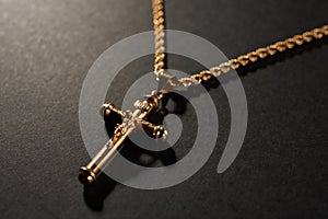 Gold cross on a chain on a black background