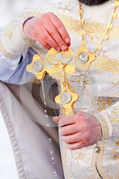 Gold cross in the hands of a priest close-up. Time to consecrate the water