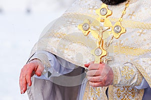 Gold cross in the hands of a priest close-up. Time to consecrate the water