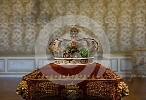 Gold crown with and jewels and gems on a royal ceremonial pillow