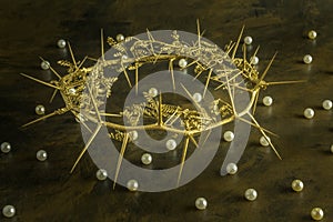 Gold crown of thorns on weathered brown background with pearls s