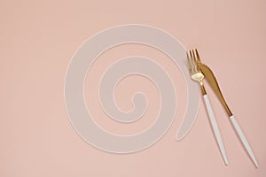 Gold cutlery. Golden spoon set, golden knife and fork on the table. Luxury spoon set top of view. Pastel punchy pink background