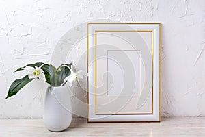 Gold decorated frame mockup with tender white lily in vase