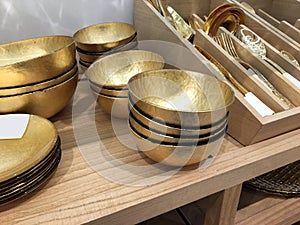 Gold decorative deep bowls. Empty metal bowls on a shelf in a store