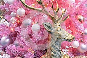 Gold deer on the background of a pink Christmas tree with white and silver balls