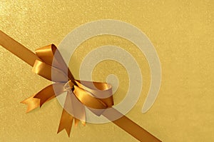 Gold diagonal corner gift bow ribbon, shiny metallic foil paper background