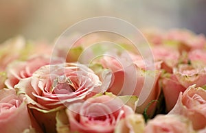 Gold diamond engagement ring in beautiful pink rose flower among big amount of roses in big bouquet close up