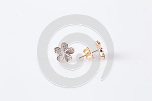 Gold earrings with diamond-shaped flowers on the white background