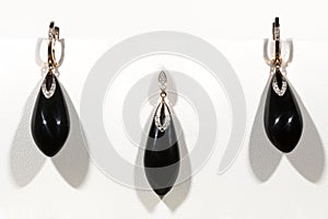 gold earrings and a pendant with onyx and diamonds on a white background. Long earrings. Jewelry set