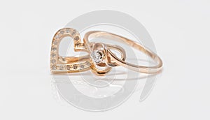 Gold earrings in the shape of a heart and a thin ring with diamond