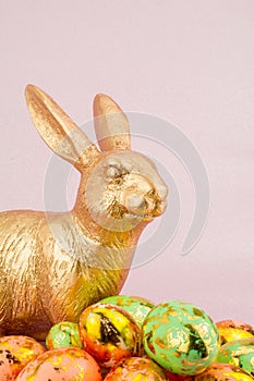 gold Easter bunny rabbit on pink background with Easter eggs