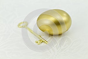 Gold egg with key on white damask