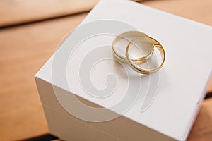 Gold engagement rings on a white and wooden background