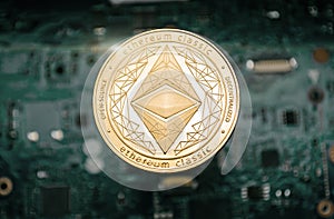 Gold etherum classic coin, on background of computer motherboard