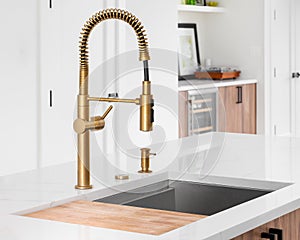 A gold faucet detail in a modern white kitchen.