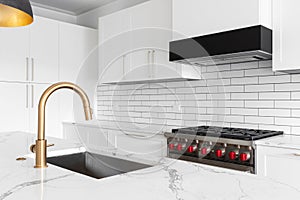 A gold faucet detail in a modern white kitchen.