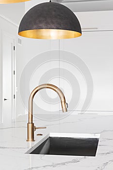 A gold faucet detail under a modern light fixture.
