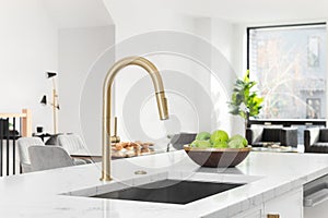 A gold faucet detail in a white kitchen.