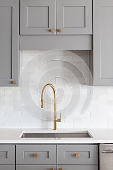 A gold faucet in a grey kitchen.