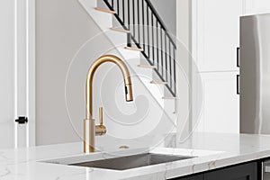 Gold faucet in a white kitchen.