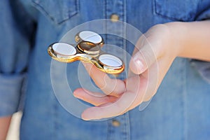 Gold fidget spinner in hand. Popular trendy toy close-up.