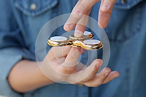 Gold fidget spinner in hand. Popular trendy toy close-up.