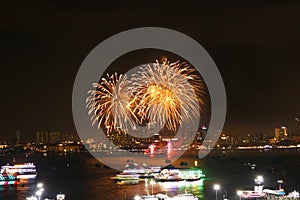 gold fireworks on beach and reflection color on water surface of light of city