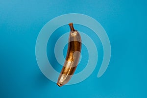 Gold floating banana on blue background. Minimal food concept