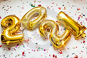 Gold foil balloons numeral 2021 with colorful confetti on white background. Happy New year 2021 celebration