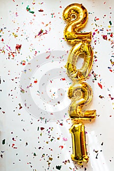 Gold foil balloons numeral 2021 with colorful confetti on white background. Happy New year 2021 celebration