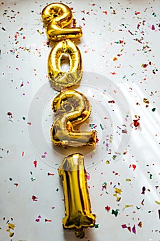 Gold foil balloons numeral 2021 with colorful confetti on white background. Happy New year 2021 celebration