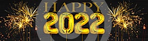 Gold foil balloons numeral 2022 and golden firework on dark black wooden texture - HAPPY NEW YEAR - Festive silvester New Year`s