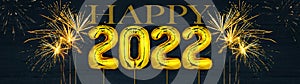 Gold foil balloons numeral 2022 and golden firework on dark blue wooden texture - HAPPY NEW YEAR - Festive silvester New Year`s