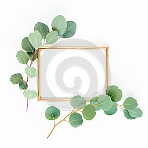 Gold frame is decorated with green branches and eucalyptus leaves on a white background. lay flat, top view